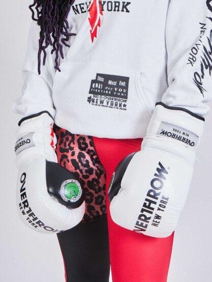female wearing white boxing gloves white sweatshirt and red leggings